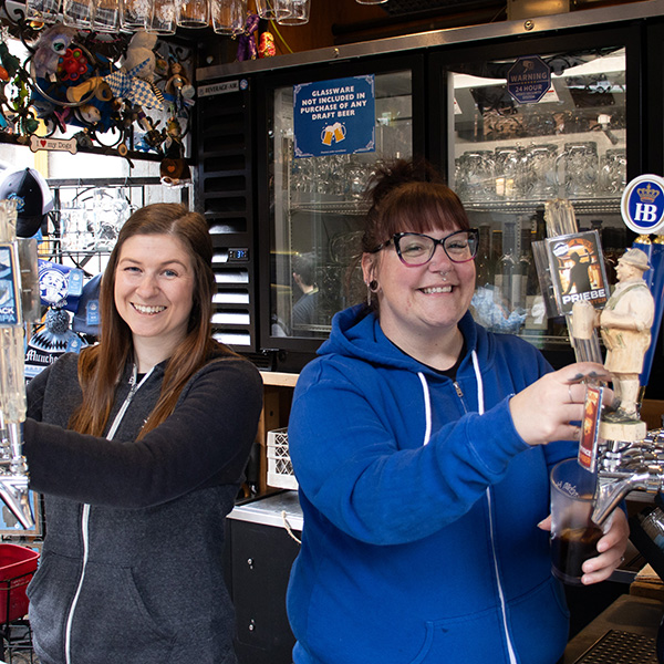 Two München Haus employees pouring beer.