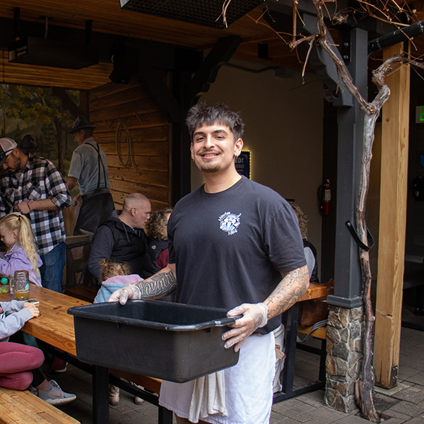 München Haus employee cleaning up dishes and smiling.
